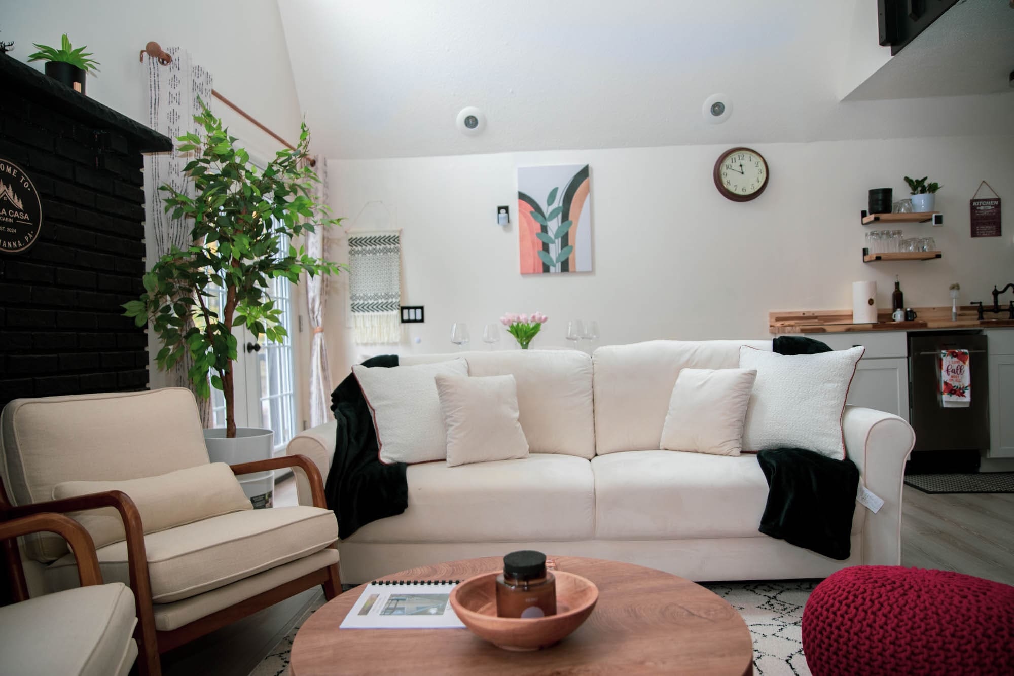 Bright living room with a white sofa, indoor plants, and A-Frame cabin wall art